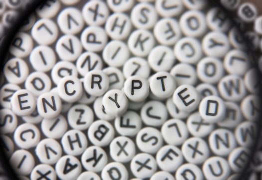 Encryption. Random alphabets under a magnyfing glass with letters of "ENCRYPTION" on top.