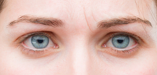 young pretty woman blue eyes close up. sad expression