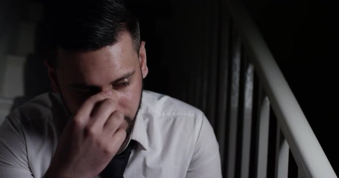 4K Close up of depressed Asian businessman sitting alone staring into the darkness