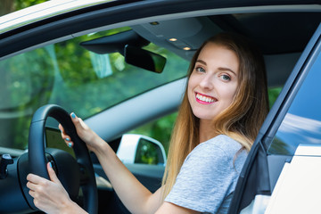Naklejka premium Happy young woman in a new luxury car