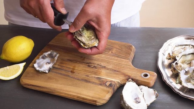someones hands open fresh raw oysters