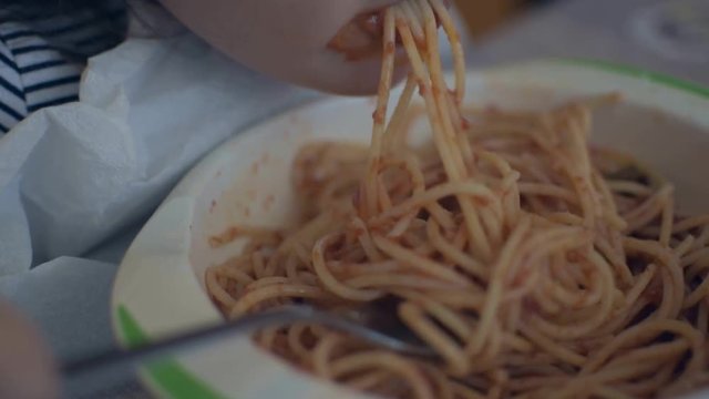 Italian baby eating tomato spaghetti.