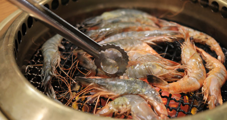 Japanese style barbecue with shrimp on metal net in restaurant