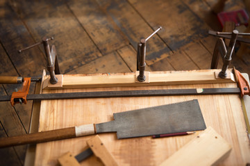 Woodworking. Wood working project on work bench, in a workshop with wooden floor. Clamped pieces of wood with c-clamps and bar clamp. shot in low key and shallow depth of field.