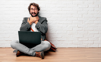 young man sitting on the floor screaming, looking surprised, stressed and terrified, with a gesture...