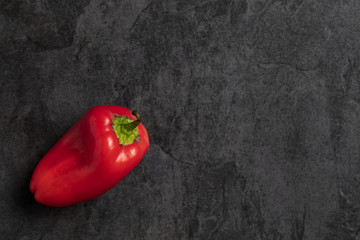 Small sweet Red bell pepper on dark stone background. Top view