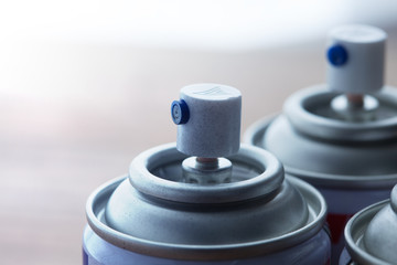 Aerosol spray cans nozzle close up. Several spray cans with light in background. Shallow depth of...