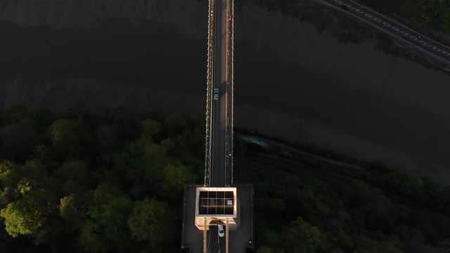 Aerial: Birds Eye of Car Driving Over Clifton Suspension Bridge Bristol City England at Sunset