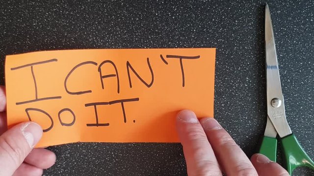 Man using scissors to remove the t from the word can't t leaving the positive motivational part. I can do it.