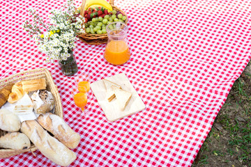 Fototapeta na wymiar picnic bread crossiant basket with fruit on red white cloth