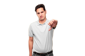 Young handsome tanned man with a dissenting, serious, stern expression, with thumbs down in...