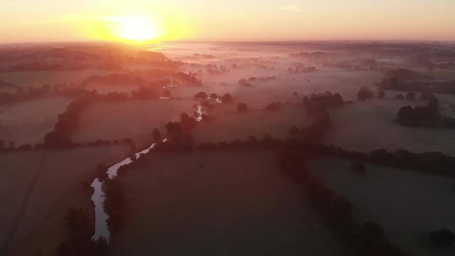 Aerial footage of low lying mist lying in the East Anglian countryside at sunrise.