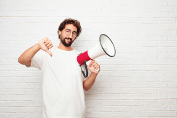 young dumb man with a dissenting, serious, stern expression, with thumbs down in disapproval.