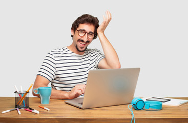 young bearded graphic designer with a laptop happily realizing some good and surprising news or...