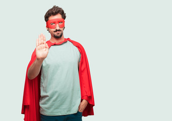 crazy man as a super hero Signaling stop with the palm of hand facing forward, with a serious and...