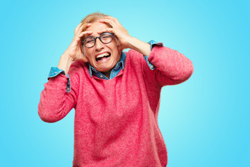 Beautiful adult blonde woman with a crazy, amazed look of surprise, holding head with both hands, pulling hair.