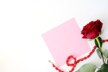 Card for Valentine's Day. A red rose on a white background with a beads.