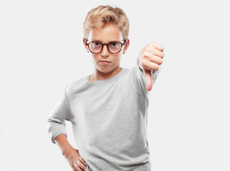 young blonde handsome boy with a dissenting, serious, stern expression, with thumbs down in...