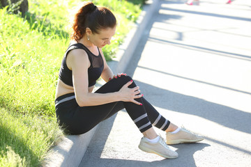 Beautiful athletic girl holding on to knee after injury