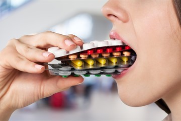 Girl eating lots of pills on background