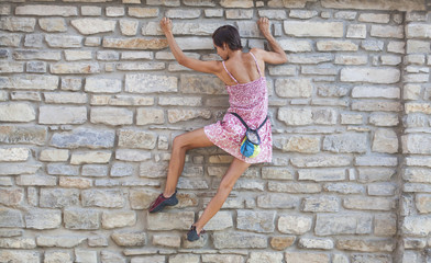 The girl climbs the stone wall.
