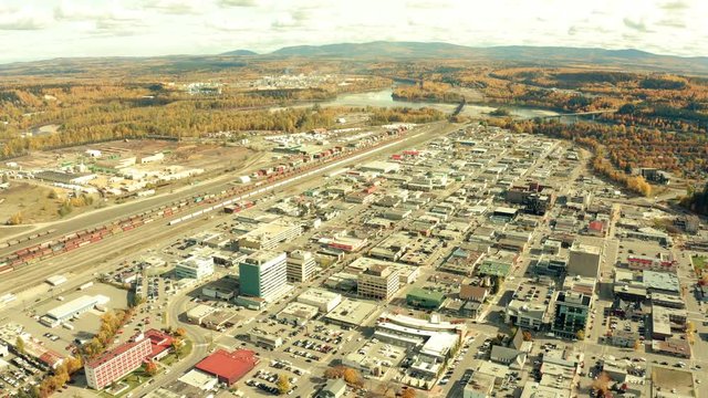 A cinematic, aerial view of the city of Prince George downtown area, including the train yard and outlying pulp mill during the autumn / fall season.