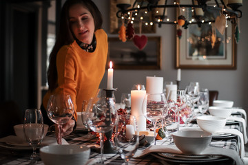 Young woman placing wine glass on holiday dinner table