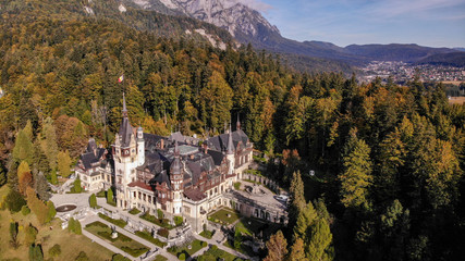 Fototapeta na wymiar Aerial view of Peles Castle in Sinaia, Carpathian mountains, Brasov region, Romania. Beautiful autumn landscape in castle surrounded with the forest and high mountains.