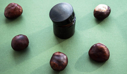 a jar of cream and chestnuts on a green background
