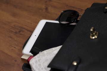 女性用の小さなバッグとタブレットパソコンとサングラスと化粧ポーチ