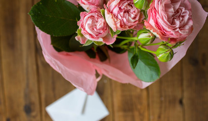 a roses in a vase with envelope on wooden grey background