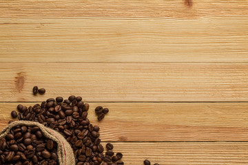 Sack of coffee beans on wooden background
