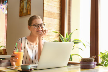 Young freelancer with laptop working in cafe