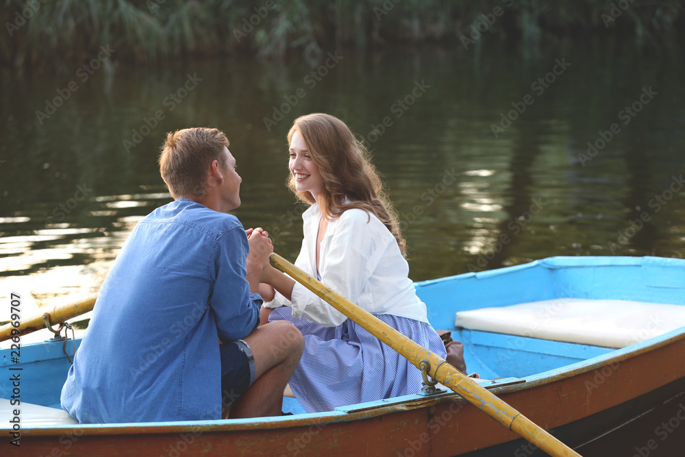 Wall mural Cute young couple having romantic date in boat