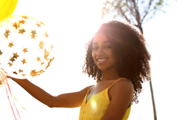 Naklejka premium Beautiful African-American woman with balloons outdoors