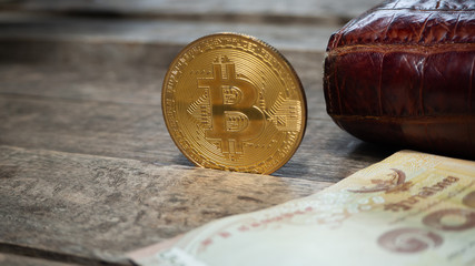 Bitcoin coin with Thailand currency on the table wood.