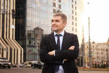 Handsome businessman with crossed arms outdoors