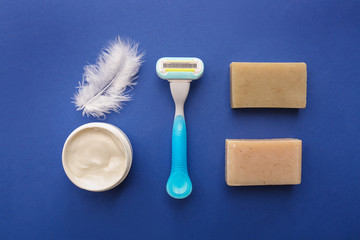Razor, soap and jar with cream on color background