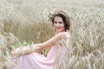 Enjoying the nature. Woman sitting in wheat field front view