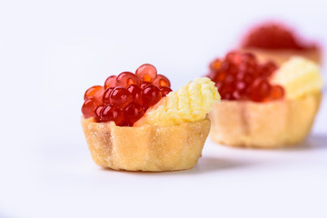 Several tartlets with red caviar and butter isolated on white background © svdolgov