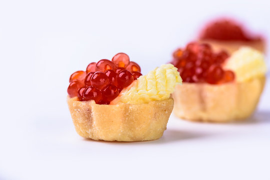 Several tartlets with red caviar and butter isolated on white background