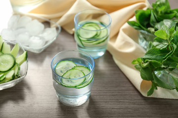 Glass of tasty fresh cucumber water on wooden table