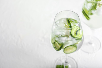 Glass with tasty cold cucumber water on white table