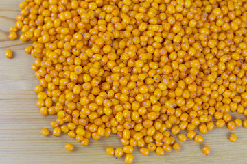 Ripe sea buckthorn is scattered on the wooden table