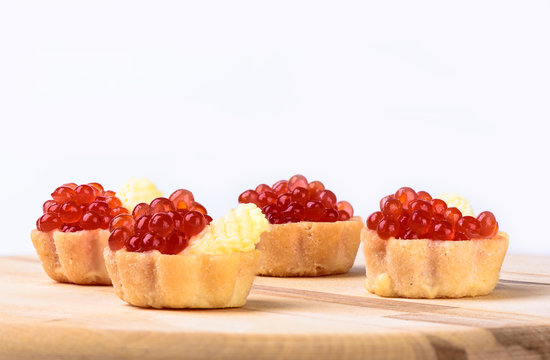 Tartlets with red caviar and butter on a cutting board