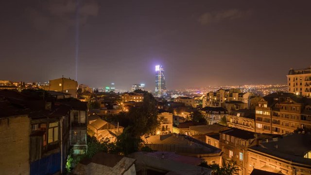 Tbilisi, Georgia old town of the city with lot of tile roofs and some modern buildings and glass skyscraper panoramic view at night shot in time lapse