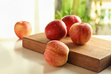 Ripe juicy apples and wooden board on table