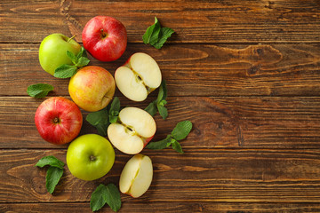 Cut and whole fresh ripe apples with mint on wooden table