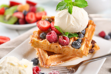 Delicious waffles with berries and ice cream on plate