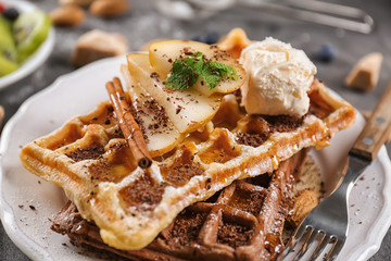 Delicious waffles with pear slices and ice cream on plate
